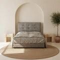 Light grey tufted bed, front view against an arched wall recess