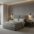 Grey upholstered bed with padded headboard in a softly lit bedroom