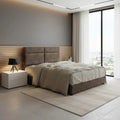 Brown upholstered bed beside a large window