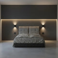 Grey upholstered bed, front view against a dark wall