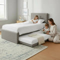 Adult and children beside a grey guest bed with trundle extended